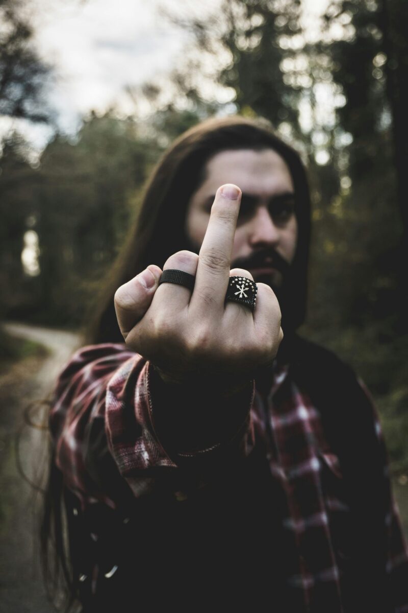 Man outdoors showing rings with hand gesture, forest background.